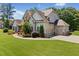 Inviting home front exterior with a three-car garage, manicured lawn, and colorful landscaping at 161 Archstone Sq, Mcdonough, GA 30253