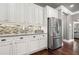 Bright kitchen featuring stainless steel refrigerator, mosaic backsplash, and white cabinets with black hardware at 161 Archstone Sq, Mcdonough, GA 30253