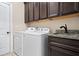 Functional laundry room with modern washer and dryer, granite countertops, and dark wood cabinets at 161 Archstone Sq, Mcdonough, GA 30253