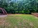 Spacious backyard with green grass, mature trees, and privacy fence. Features a patio at 4345 Park Brooke Trce, Alpharetta, GA 30022