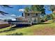 Backyard view of house with large deck, grassy lawn, and mature trees for privacy at 516 N Shore Rd, Lithonia, GA 30058