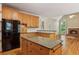 Spacious kitchen with wood cabinets, granite countertops, black appliances, and an adjacent living room with a fireplace at 980 Ector Chase Nw, Kennesaw, GA 30152