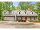 Gray home with a spacious driveway and attached garage, complemented by green landscaping and a red door at 130 River Ne Lndg, Sandy Springs, GA 30350