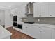 Close up of stainless steel gas stovetop and oven under range hood with white cabinets at 4708 Cooling Water Sw Cir, Powder Springs, GA 30127