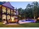 Exterior evening shot of a backyard with a pool, hot tub, fire pit, patio, and tiered landscaping at 670 Trinity Pl, Suwanee, GA 30024