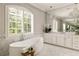 The bathroom features a soaking tub, marble floors, a large vanity with mirrors, and a large window at 670 Trinity Pl, Suwanee, GA 30024