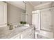 Bright bathroom featuring marble countertops, decorative mirror, and shower-tub with marble surround at 670 Trinity Pl, Suwanee, GA 30024