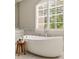 Bright bathroom features a large soaking tub under a large window with privacy shutters at 670 Trinity Pl, Suwanee, GA 30024