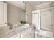 Bright bathroom featuring a white vanity with marble countertop, tub with shower, and decorative marble-look tiled walls at 670 Trinity Pl, Suwanee, GA 30024