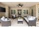 Comfortable covered patio with brick walls, plush seating, ceiling fan, and an outdoor television at 670 Trinity Pl, Suwanee, GA 30024