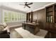 Spacious office featuring custom dark wood built-ins, a leather chair, and large window with plantation shutters at 670 Trinity Pl, Suwanee, GA 30024
