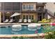 Backyard pool featuring lounge chairs, an umbrella, landscaped backyard, and a two-story brick home at 670 Trinity Pl, Suwanee, GA 30024