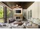 Relaxing screened porch with stone fireplace, dark stained wood ceiling, and comfortable seating area at 670 Trinity Pl, Suwanee, GA 30024