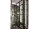 A modern wine cellar with black framed glass doors and wine racks displaying numerous bottles and elegant stemware at 670 Trinity Pl, Suwanee, GA 30024