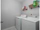 Bright laundry room featuring a white washer and dryer with shelving above, perfect for organization at 1535 Justine Se Way, Mableton, GA 30126