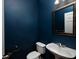 Stylish powder room featuring a pedestal sink, framed mirror, and elegant deep blue walls at 1535 Justine Se Way, Mableton, GA 30126