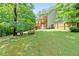 Serene backyard with mature trees, a wooden bench, and a spacious lawn, ideal for relaxation and outdoor gatherings at 596 Deadwood Trl, Locust Grove, GA 30248