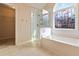 Bright bathroom with a shower, a bathtub, stained glass window, and an entrance to the closet at 7325 Thoreau Cir, Atlanta, GA 30349
