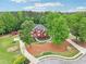 Aerial view of the brick home nestled amongst mature trees with a long driveway and green lawn at 1424 Brighton, Loganville, GA 30052