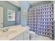 Bright bathroom featuring a single sink vanity, mirror, and bathtub with a geometric patterned shower curtain at 1424 Brighton, Loganville, GA 30052