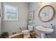 Stylish powder room featuring a pedestal sink and a round mirror, with wood look floor at 1424 Brighton, Loganville, GA 30052