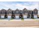 New row of townhomes with neutral exteriors, brick accents, and white garage doors at 231 Ivey Ter, Temple, GA 30179