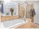 Main bathroom featuring a garden tub, glass shower, and decorative window at 4445 Vanadium Bend, Cumming, GA 30040