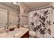 This bathroom has a dark wood vanity, white toilet, and shower with a leaf patterned curtain at 2020 Walking Horse Trl, Cumming, GA 30041