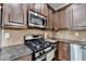 Close-up of a kitchen featuring dark cabinets, stone countertops, and stainless-steel appliances at 2020 Walking Horse Trl, Cumming, GA 30041
