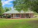 Attractive brick home with a long, covered front porch, surrounded by lush landscaping at 2620 Dr Bramblett Rd, Cumming, GA 30028