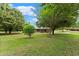 Lush front lawn with mature trees framing a charming brick home with a covered front porch at 2620 Dr Bramblett Rd, Cumming, GA 30028