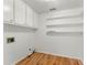 Efficient laundry room featuring hardwood floors, ample shelving, and overhead storage cabinets at 2620 Dr Bramblett Rd, Cumming, GA 30028