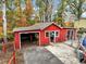 Red outdoor shed with an open garage bay door and personal door and chain-link fence at 2775 Hogan Rd, Atlanta, GA 30344