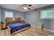 Bedroom with blue walls, wood floors, a ceiling fan, and two windows with blinds at 3861 Hanover Ct, Marietta, GA 30062