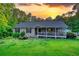 Charming single-story home with a covered porch and lush landscaping at sunset at 160 Riverbrooke Trl, Covington, GA 30016