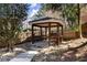 Gazebo in backyard sitting on rocks surrounded by lush greenery and trees at 300 Morganshire Pl, Atlanta, GA 30350