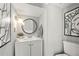 Stylish half bathroom featuring a modern vanity, round mirror, and contemporary artwork at 4131 N Gloucester Pl, Atlanta, GA 30341