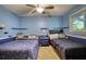 This cozy blue bedroom features two beds, shelves, ceiling fan, and large window with natural light at 2368 Ellis Court, Snellville, GA 30078