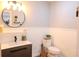 Bathroom featuring a modern vanity, round mirror, toilet, and wainscoting for a clean and stylish design at 762 Thompson Ln, Loganville, GA 30052
