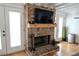 Living room features a brick fireplace, a mounted TV, wood floors, and white doors to the outside at 762 Thompson Ln, Loganville, GA 30052