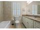 Bright bathroom with white cabinets, granite countertop, tiled bathtub, and plantation shutters at 9056 Riverbend Mnr, Alpharetta, GA 30022