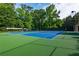 Blue and green tennis courts surrounded by lush green trees in a gated community at 9056 Riverbend Mnr, Alpharetta, GA 30022