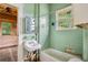 Aqua-tiled bathroom with a vintage sink, bathtub, and natural light from the window at 1792 Center Ave, East Point, GA 30344
