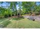 Large, grassy backyard featuring a retaining wall, garden beds, and mature trees for shade at 5725 Lake Oak Lndg, Cumming, GA 30040