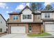 Beautiful two-story townhome featuring stone accents, white siding, and a two-car garage at 8210 Sonata Ln, Cumming, GA 30041
