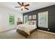 Inviting bedroom featuring a wood accent wall, plush carpet, and abundant natural light from two windows at 6715 Pond Rd, Cumming, GA 30040