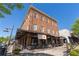 Three-story brick building with outdoor seating and awnings under a clear blue sky, offering a welcoming and vibrant atmosphere at 6715 Pond Rd, Cumming, GA 30040