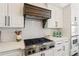 Modern kitchen boasts stainless steel gas range and custom wood vent hood with white tile backsplash at 6715 Pond Rd, Cumming, GA 30040