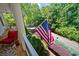 Cozy porch featuring a comfortable chair and American flag with lovely views of manicured landscaping at 6715 Pond Rd, Cumming, GA 30040