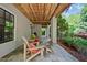 Inviting covered porch with stone flooring and comfortable seating area with wood ceiling and lush landscaping at 6715 Pond Rd, Cumming, GA 30040